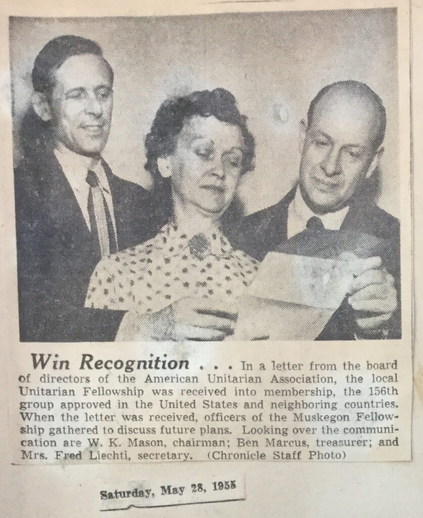 A black and white newspaper clipping with an image of three people looking at a document, a woman in the middle and two men on either side of her.